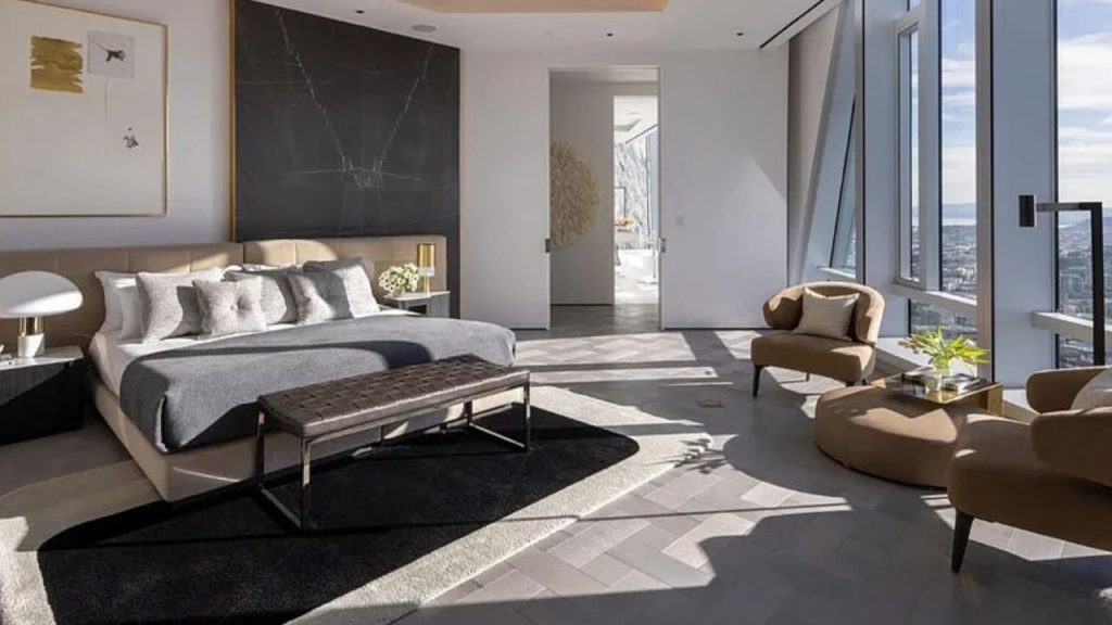 A cozy bedroom with a plush bed, black marble wall, and large windows showcasing a city view.