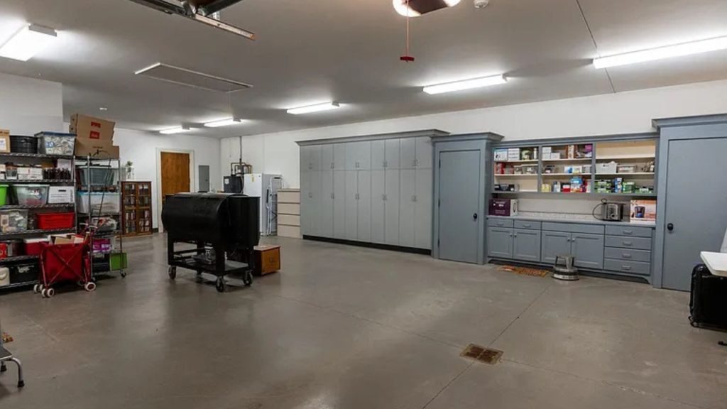 A tidy garage with cabinets, tools, and a smoker.