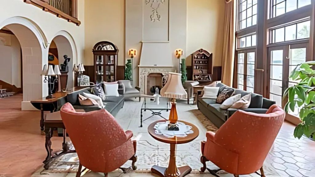 A cozy living room with red armchairs, a fireplace, and large windows.