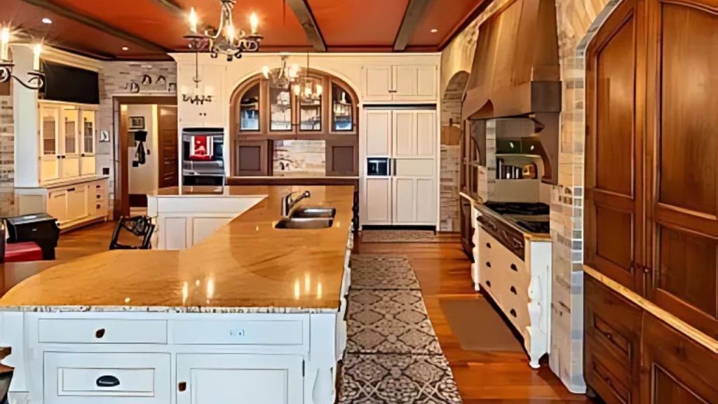 A rustic kitchen with a wooden island, chandeliers, and stone accents.