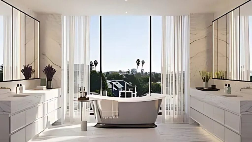 A luxurious bathroom with a freestanding tub, marble vanities, and large windows overlooking palm trees.