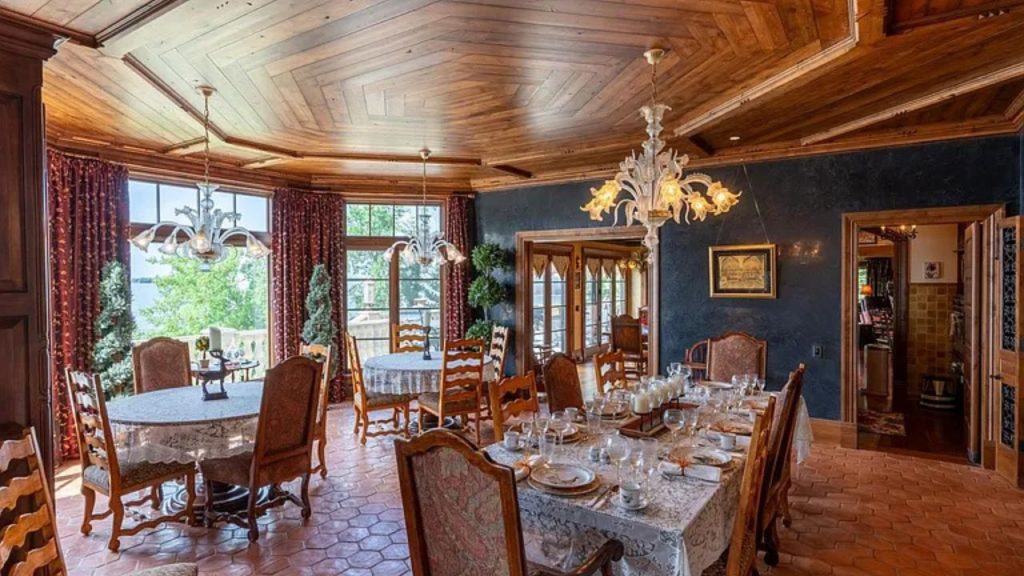 A stylish dining area with wooden ceiling, chandeliers, and large windows.