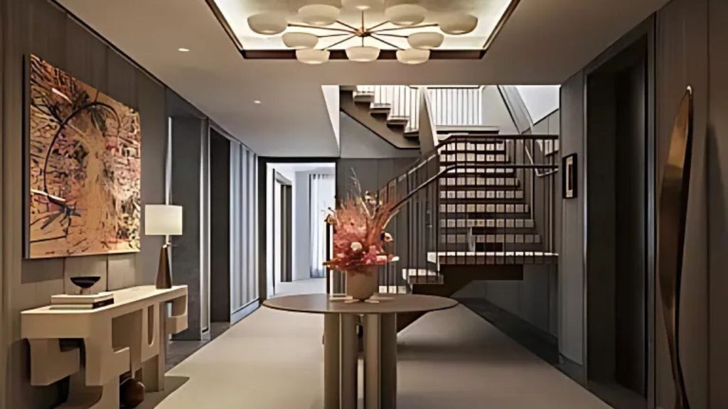 A modern hallway with a chic chandelier, abstract art, and a floral centerpiece near a stylish staircase.