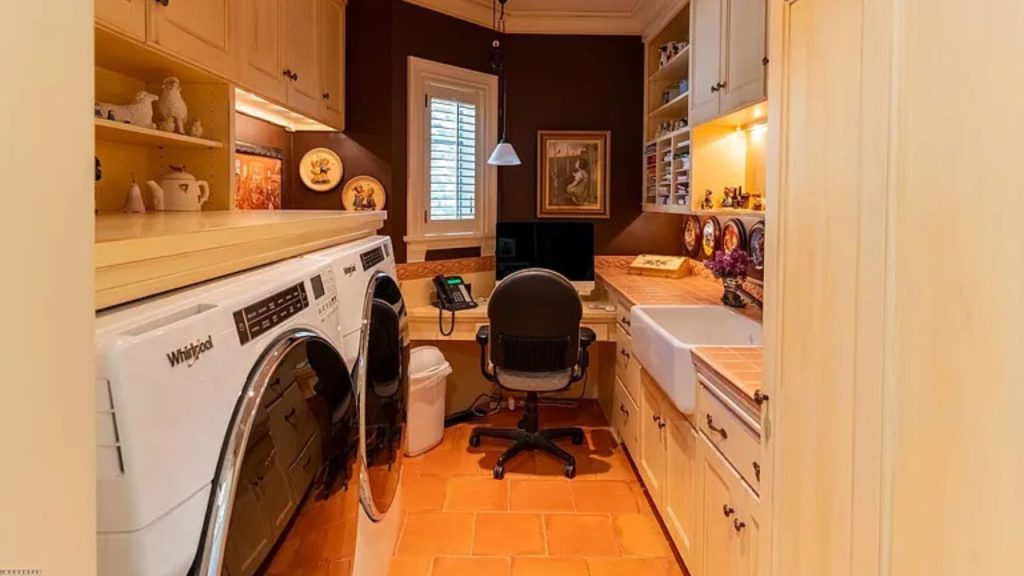 A cozy laundry nook with washer, desk, and decorative shelves.