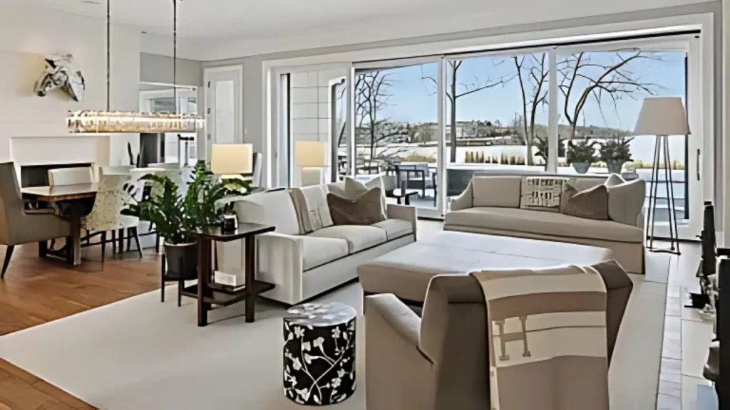 A bright living area with large windows, cozy sofas, and a dining space.
