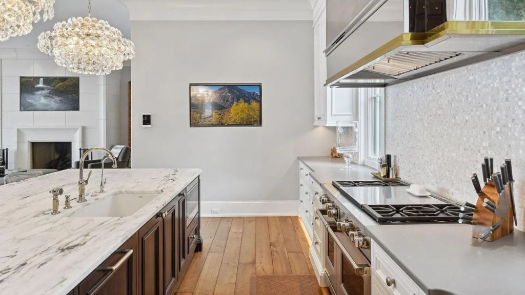 A luxurious kitchen with a marble island, chandeliers, and a mountain view.