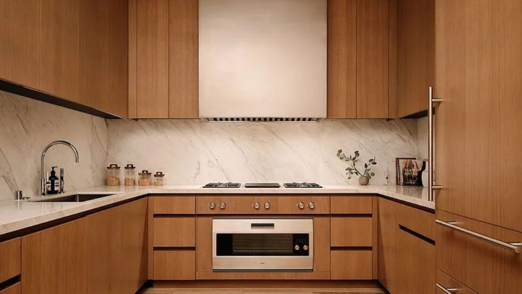 A sleek kitchen with wooden cabinets, marble backsplash, gas range, and modern sink.