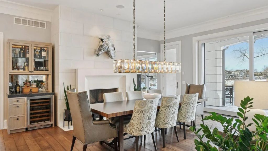 A cozy dining room with a wooden table, chandelier, and fireplace.