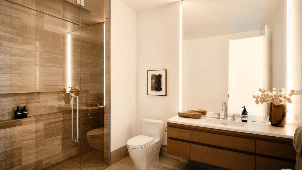 A serene bathroom with a glass shower, wooden vanity, and dried flower decor.