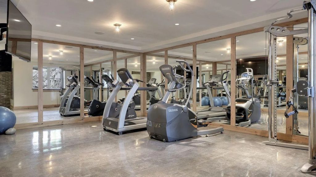 A modern home gym with mirrored walls and exercise equipment.