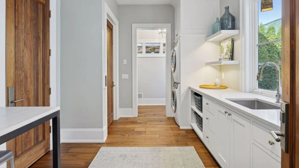 A tidy laundry room with a sink, washer, and open shelves.