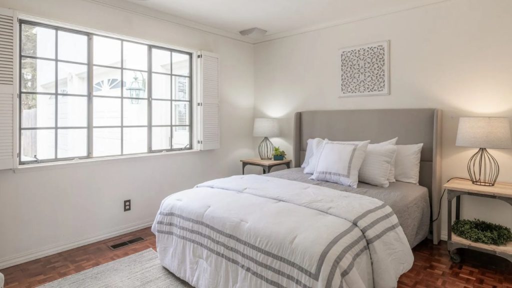 A serene bedroom with large windows and a plush bed.