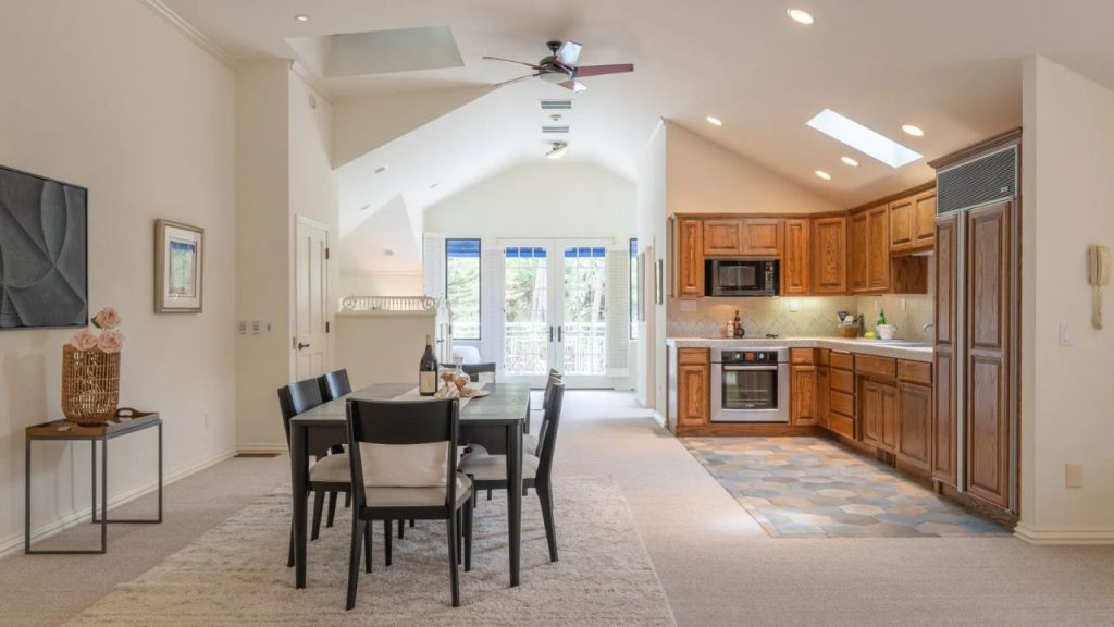 A bright kitchen and dining area with wooden cabinets and a view to the outdoors.