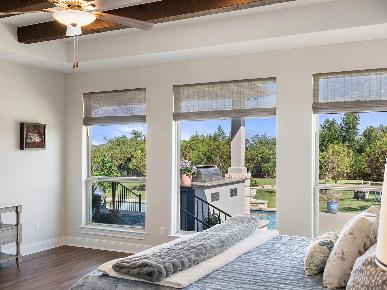 Master bedroom with large windows overlooking the outdoor patio and pool area