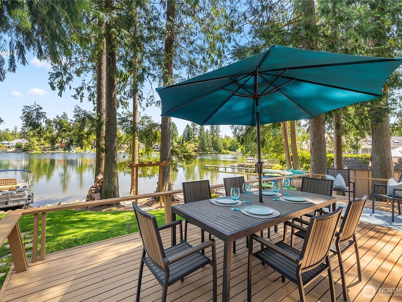 Outdoor dining table with umbrella on a deck overlooking a lake
