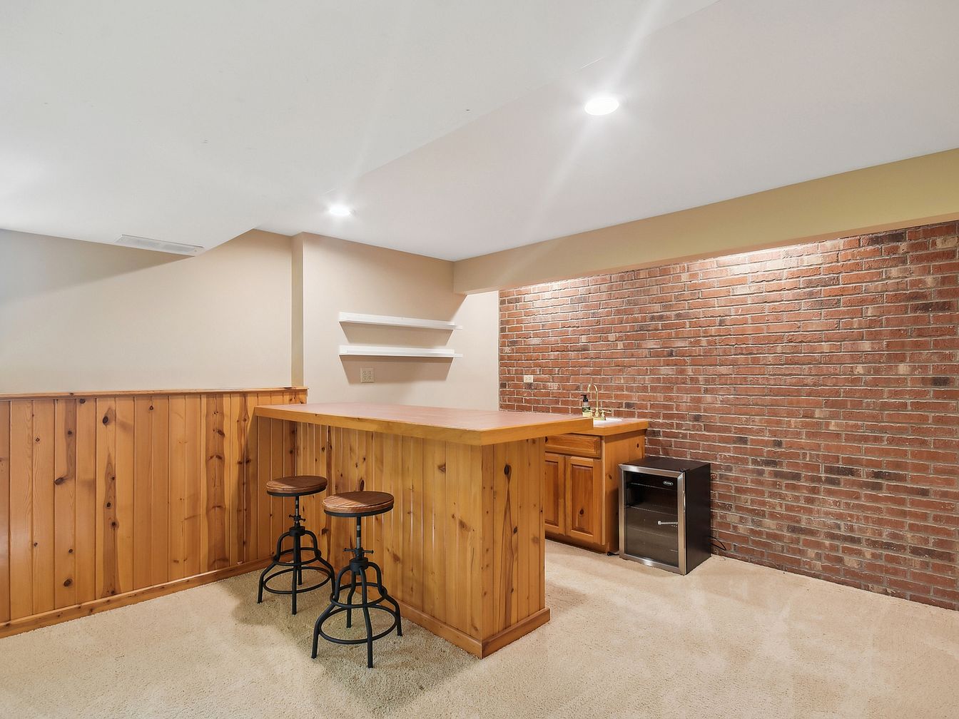 Cozy basement bar with wooden countertop and brick wall