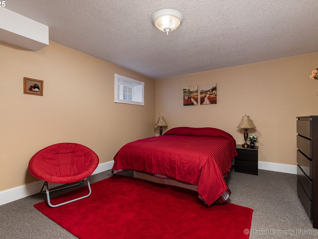 Basement bedroom with red bedding and chair