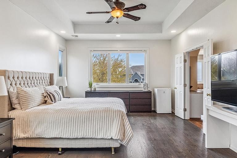Master bedroom with tufted bed, dresser, TV, and ceiling fan