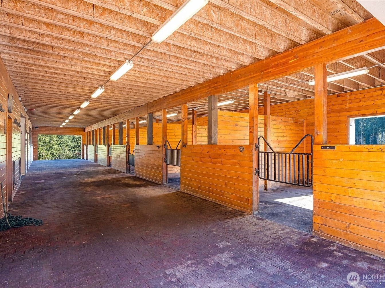 Interior of an equestrian stable with wooden stalls and natural lighting