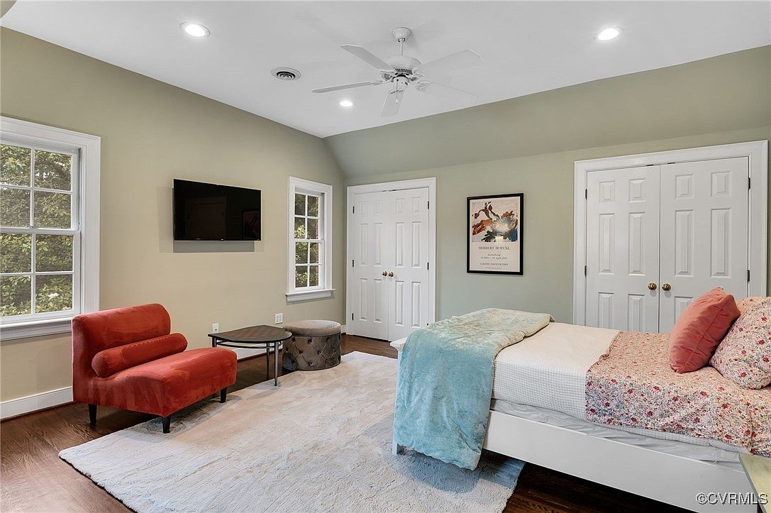 Cozy bedroom corner with a red velvet accent chair and wall-mounted TV