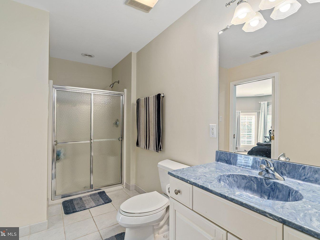 Bathroom vanity with blue countertop and shower with glass doors