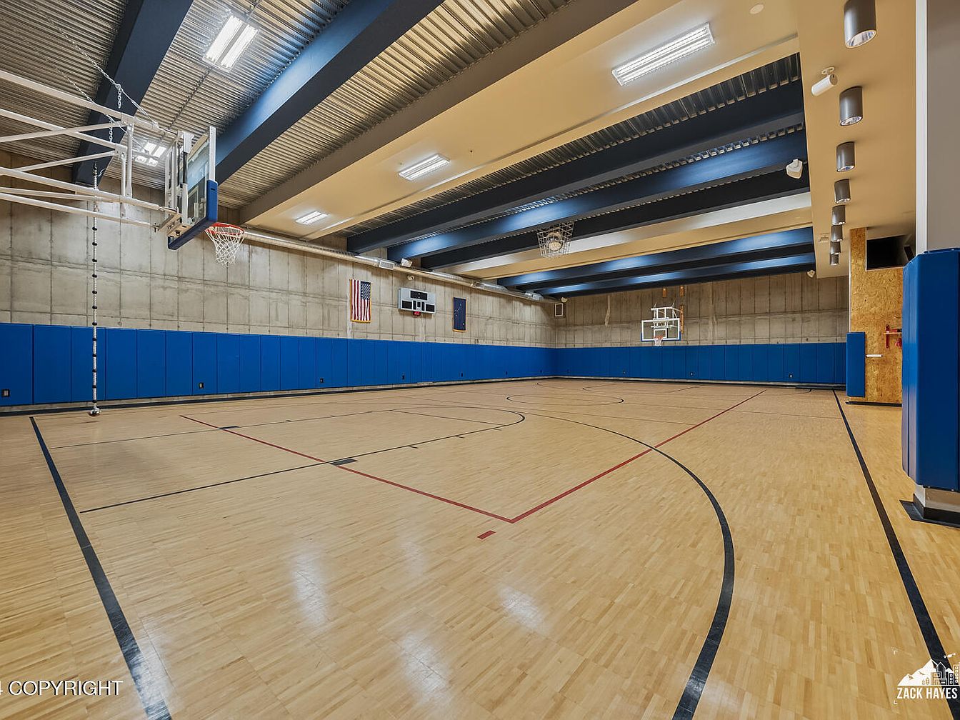 Spacious indoor basketball court with blue wall padding and wood flooring