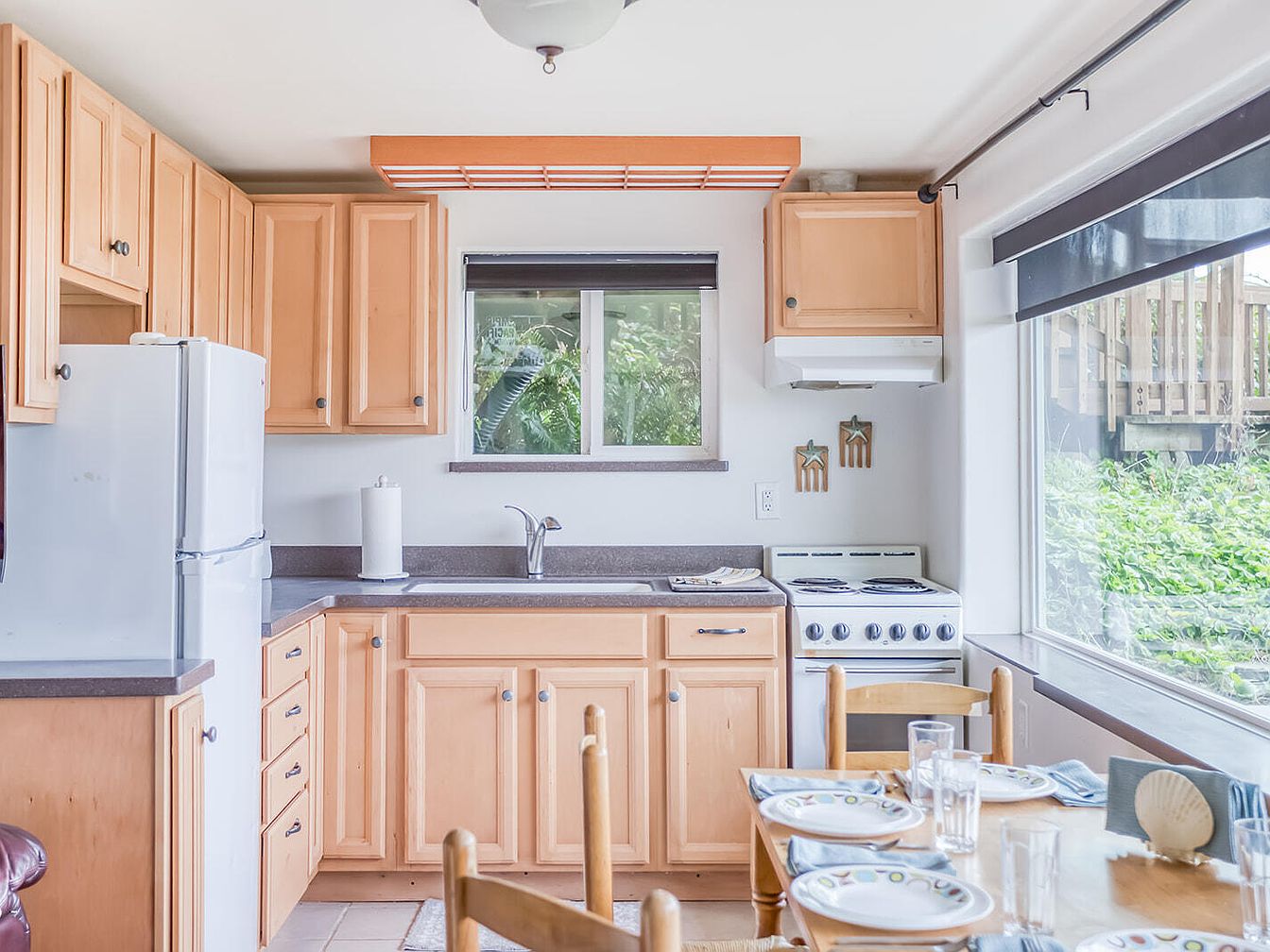 Light wood kitchen cabinets with dining table and large window view of greenery