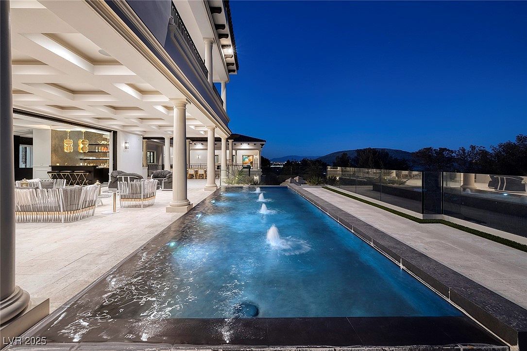 Outdoor pool area with lounge seating and nighttime lighting