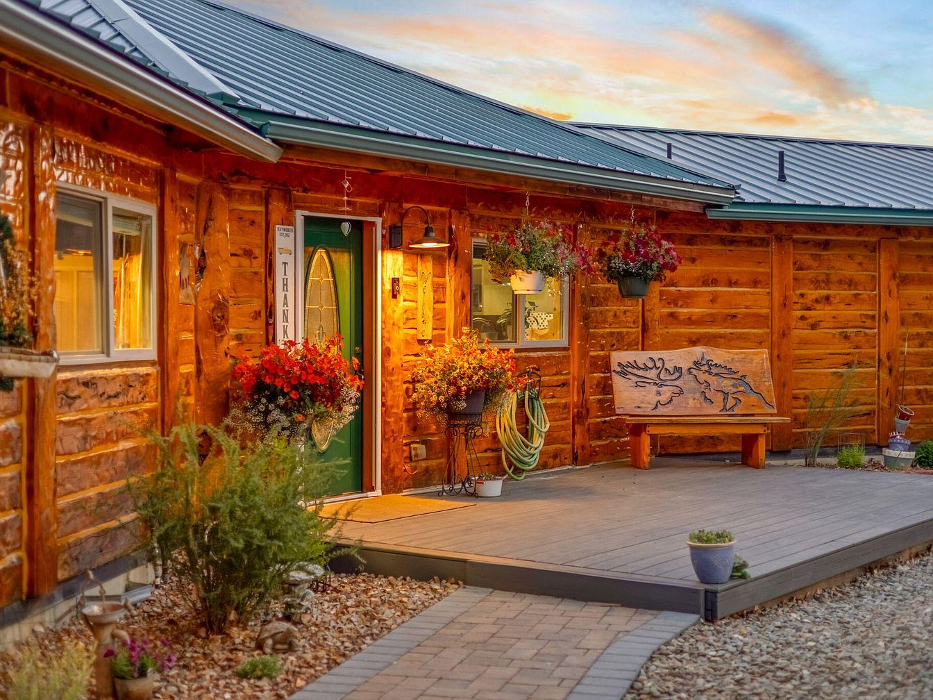 Front porch of a log cabin-style home with warm lighting and floral decorations