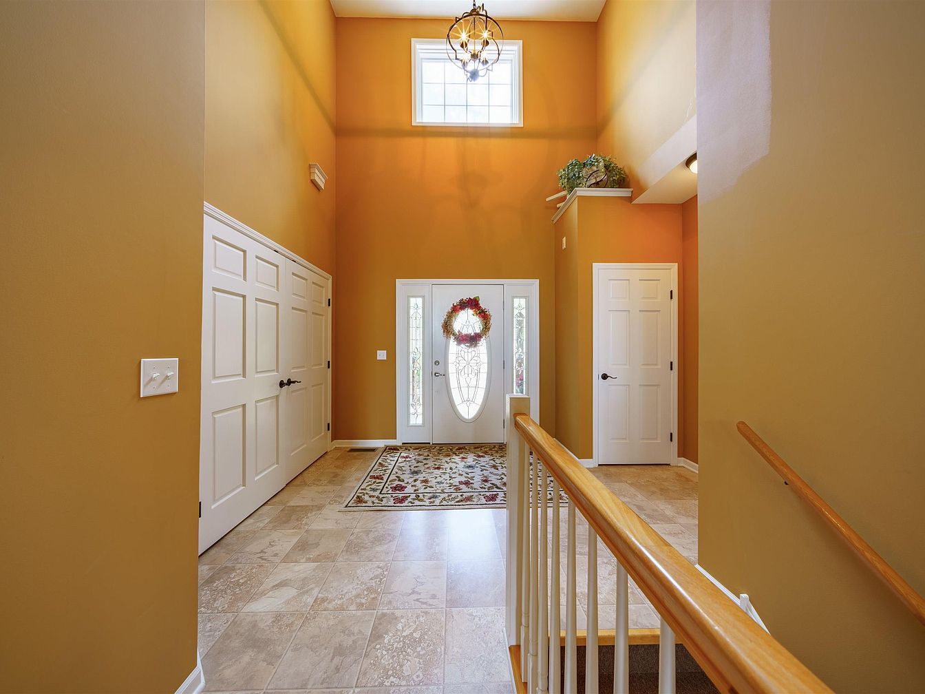 Bright entryway foyer with white front door and floral wreath